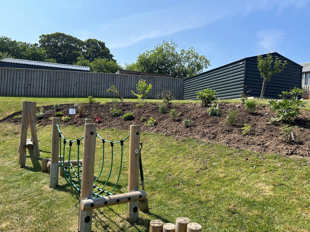 New garden bed planted with young trees, shrubs and flowering plants at The Steading.