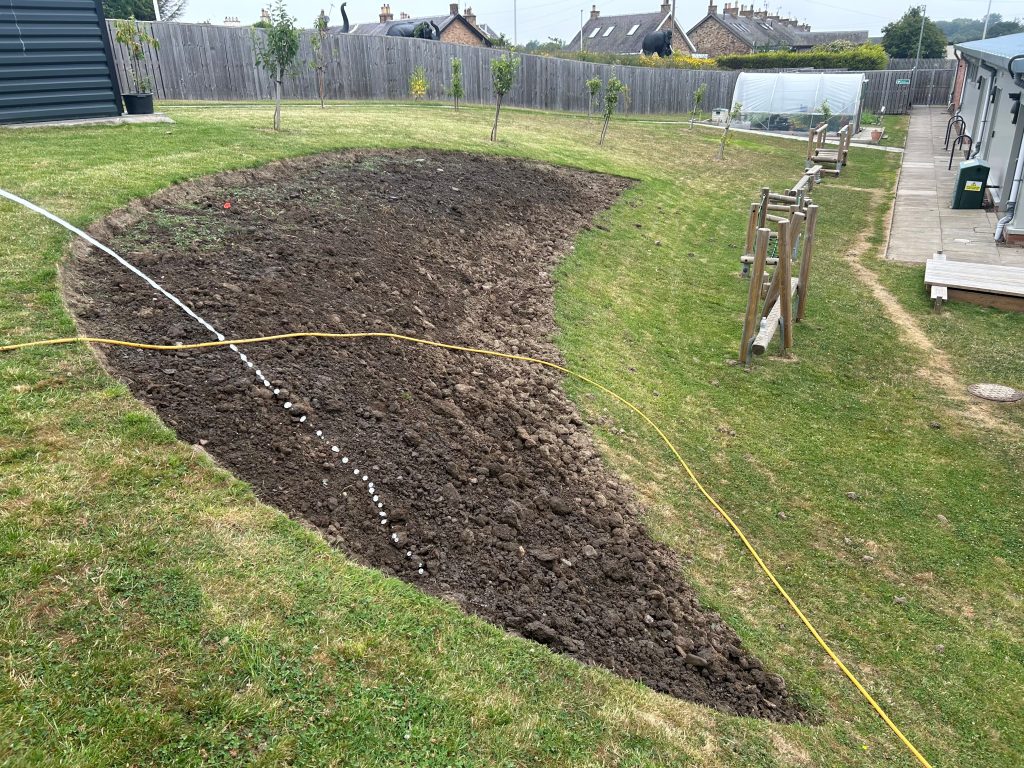Prepared garden bed on the bank beside the outdoor play area before planting.
